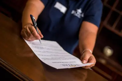 a person signing a piece of paper with a pen at Royal Aparthotel City Centre in Rhodes Town