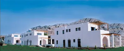 a white building with a mountain in the background at Katikies Studios & Apartments in Lardos