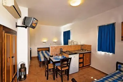 a kitchen and living room with a table and a kitchen and a dining room at Katikies Studios & Apartments in Lardos