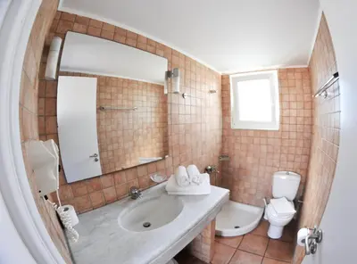 a bathroom with a sink and a toilet and a mirror at Katikies Studios & Apartments in Lardos