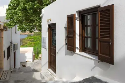 a white building with brown shutters and a window at Lindos Shore Junior Suite in Líndos