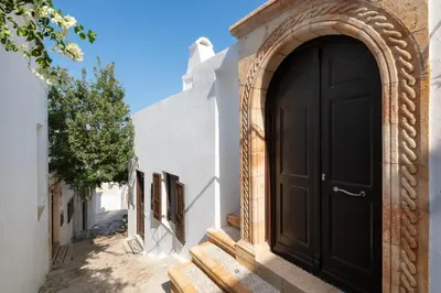 a black door on the side of a white building at Lindos Shore Junior Suite in Líndos