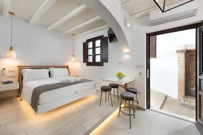 a bedroom with a bed and a table and chairs at Lindos Shore Junior Suite in Líndos