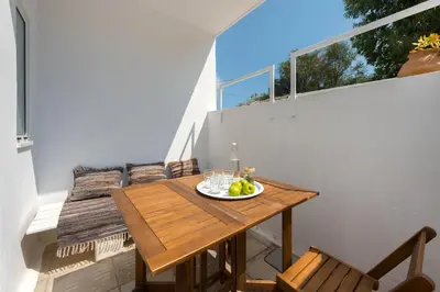 a small balcony with a wooden table and chairs at Vamare Beachfront House in Gennadi