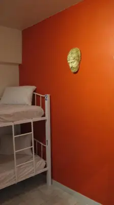 a room with two bunk beds and an orange wall at Rhodes Backpackers Boutique Hostel and Apartments in Rhodes Town