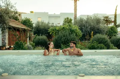 a man and a woman sitting in a swimming pool at Caesars Gardens Hotel & Spa - Adults Only in Líndos