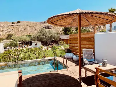 a patio with a table and an umbrella and a pool at Caesars Gardens Hotel & Spa - Adults Only in Líndos