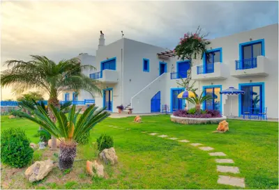 a large white building with blue windows and a yard at Bella Vista Stegna in Archangelos