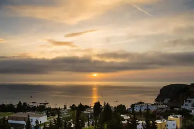 a sunset over the ocean with the sun in the sky at Bella Vista Stegna in Archangelos