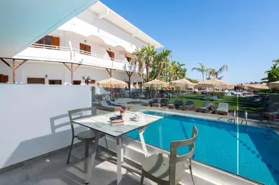 a patio with a table and chairs next to a swimming pool at Aquarius Beach Hotel in Faliraki