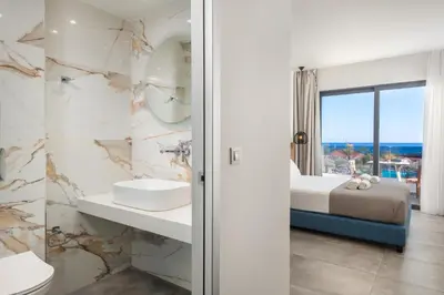 a bathroom with a bed and a sink and a mirror at Aquarius Beach Hotel in Faliraki