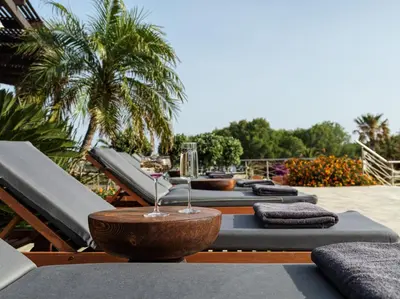 a row of chaise lounges with a wine glass on top at Aulus Lindos Rhodes, All-Inclusive Resort, Curio Collection by Hilton in Kiotari