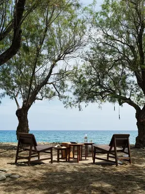 a picnic table and chairs on the beach at Aulus Lindos Rhodes, All-Inclusive Resort, Curio Collection by Hilton in Kiotari