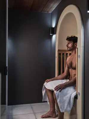 a shirtless man sitting in a bath tub at Aulus Lindos Rhodes, All-Inclusive Resort, Curio Collection by Hilton in Kiotari