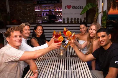 a group of people holding up drinks at a table at Hotel Parthenon Rodos city in Rhodes Town