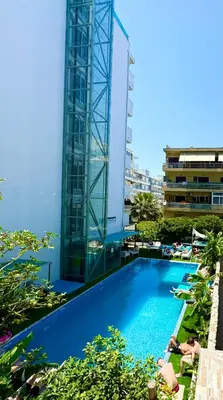 a large swimming pool next to a tall building at Hotel Parthenon Rodos city in Rhodes Town