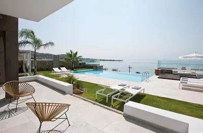 a patio with chairs and a swimming pool and the ocean at Elements Villas in Lardos