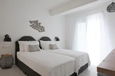 a white bedroom with a large bed with white sheets at Elements Villas in Lardos