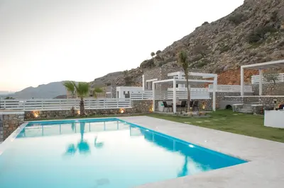 a hotel with a swimming pool in front of a mountain at Elements Villas in Lardos