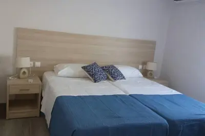 a bedroom with a blue and white bed with two pillows at Nianthy Apartments in Faliraki