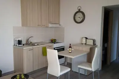 a kitchen with a table and chairs and a clock on the wall at Nianthy Apartments in Faliraki