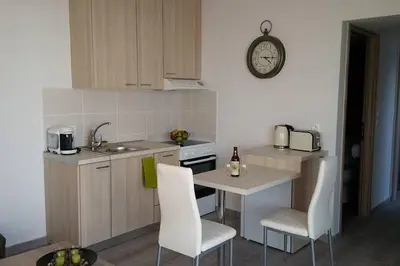 a kitchen with a table and chairs and a clock on the wall at Nianthy Apartments in Faliraki