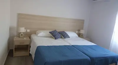 a bedroom with a large bed with blue sheets and pillows at Nianthy Apartments in Faliraki