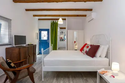 a bedroom with a white bed and a chair at Casita Del Sol Suites in Rhodes Town
