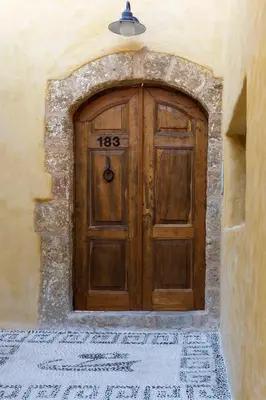 a large wooden door in a building with a tile floor at Casita Del Sol Suites in Rhodes Town