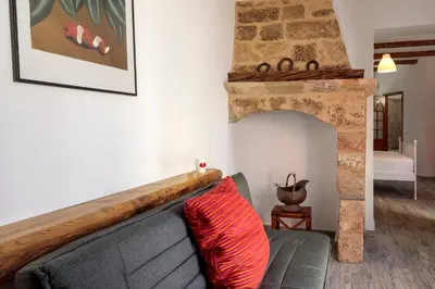 a living room with a gray couch and a stone fireplace at Casita Del Sol Suites in Rhodes Town