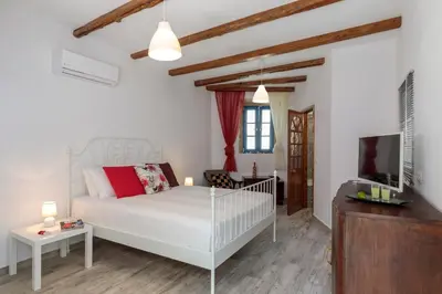a white bedroom with a bed and a tv at Casita Del Sol Suites in Rhodes Town