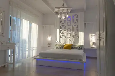 a white bedroom with a bed and a chandelier at Seva's House in Psinthos
