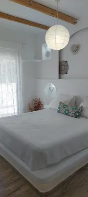 a large white bed in a white room with a window at Seva's House in Psinthos
