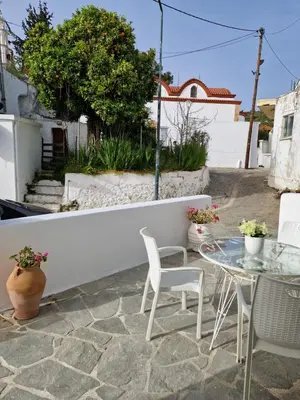a patio with a table and chairs and a white wall at Seva's House in Psinthos