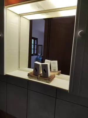 a bathroom mirror with two alarm clocks on a shelf at Tilos Fantasy in Livadia