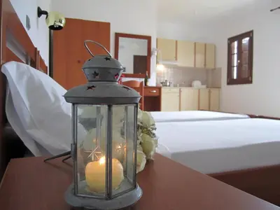 a candle in a glass jar on a table next to a bed at Tilos Fantasy in Livadia