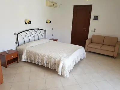 a bedroom with a bed and a couch and a chair at Tilos Fantasy in Livadia