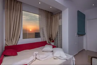 a bedroom with a bed with a red couch and a window at Sea and the city in Rhodes Town