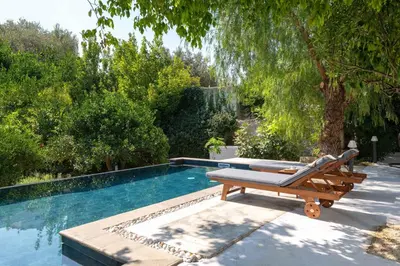 a wooden bench sitting next to a swimming pool at Villa Eleonora in Rhodes Town