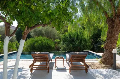 two chairs and a table next to a swimming pool at Villa Eleonora in Rhodes Town