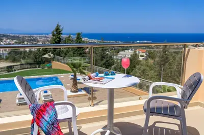 a balcony with a table and chairs with a glass of wine at Aegean Blue Villa in Koskinou