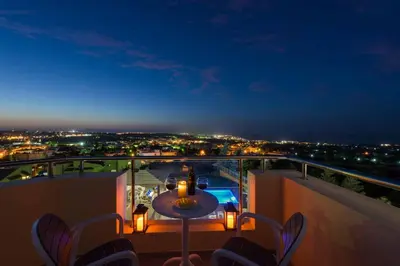 a balcony with a table and chairs at night at Aegean Blue Villa in Koskinou