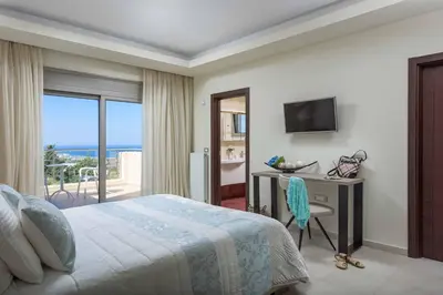 a bedroom with a bed and a desk and a television at Aegean Blue Villa in Koskinou