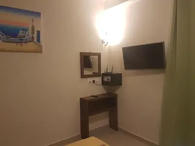 a room with a tv on a wall with a table at Maestro Apartments Faliraki in Faliraki
