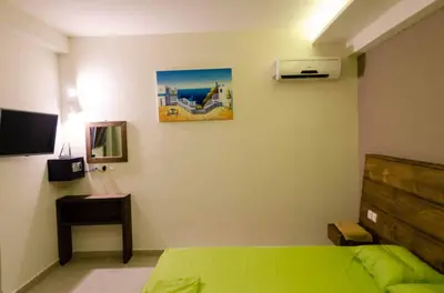 a bedroom with a green bed and a tv at Maestro Apartments Faliraki in Faliraki