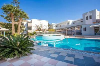 a swimming pool in front of a building with palm trees at Irinna Hotel-Apartments in Faliraki