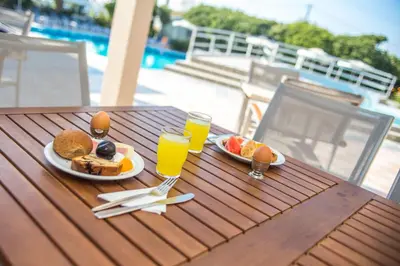 a table with two plates of food and glasses of orange juice at Irinna Hotel-Apartments in Faliraki