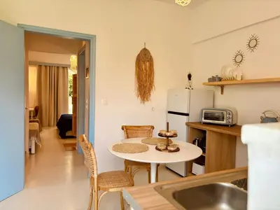 a kitchen with a table and a small kitchen with a refrigerator at Afroditi Junior Suites in Archangelos