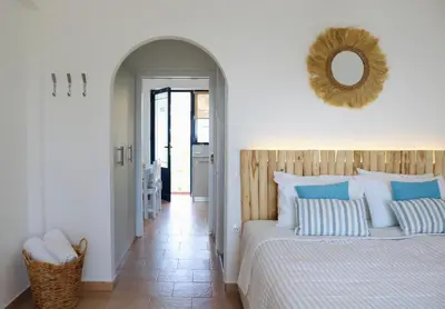 a bedroom with a bed and a mirror on the wall at Afroditi Junior Suites in Archangelos