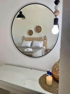 a mirror in a bedroom with a bed and a candle at Afroditi Junior Suites in Archangelos